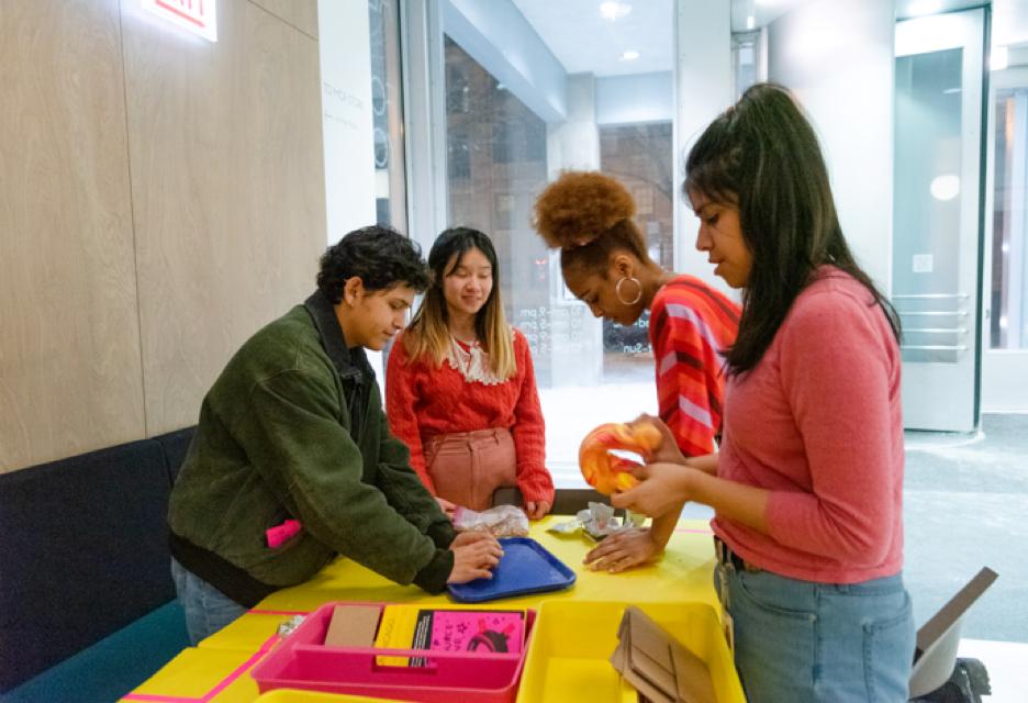 four teens work on a project gathered around a table