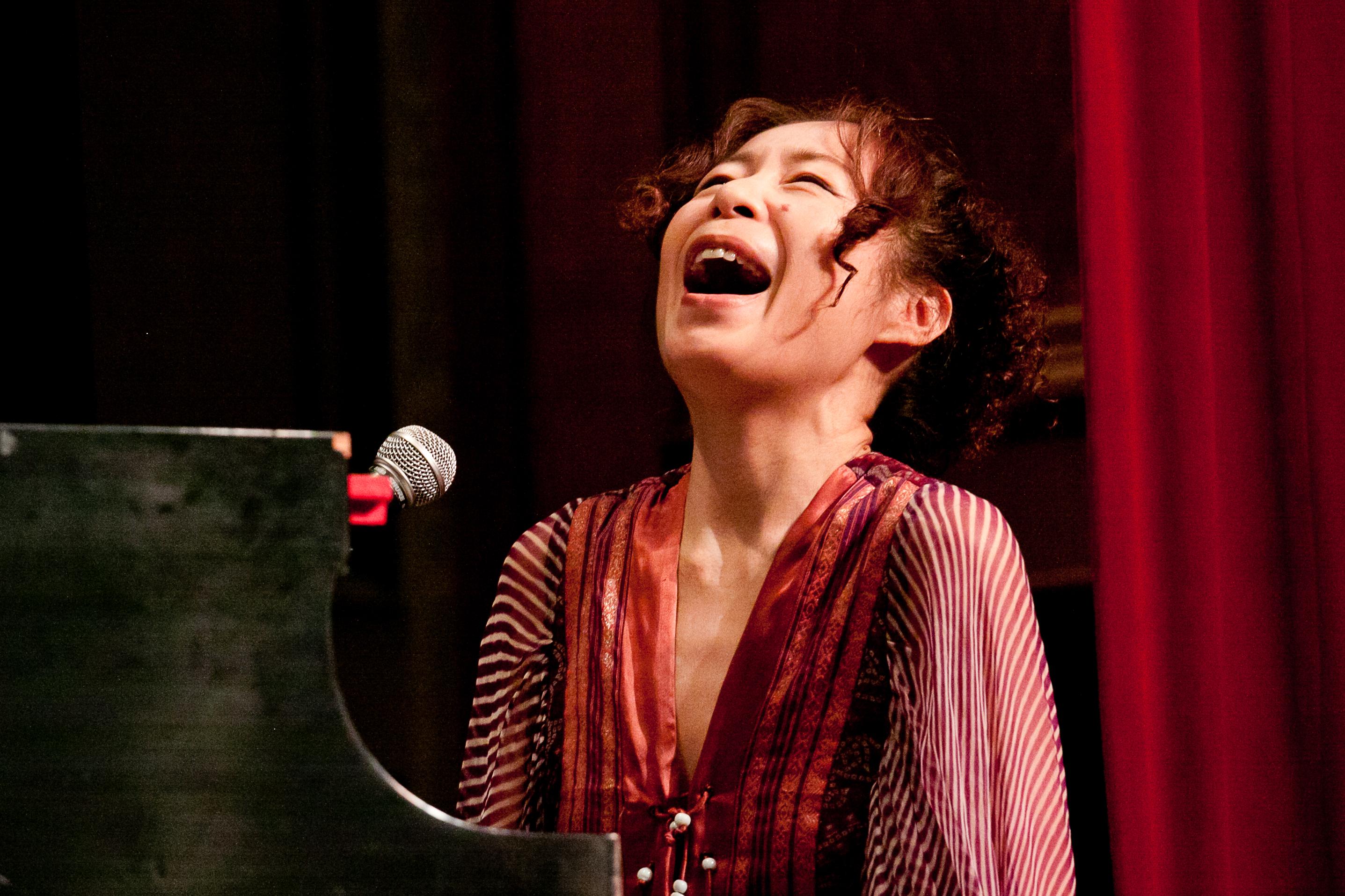 Yoko Noge sings powerfully while sitting at piano
