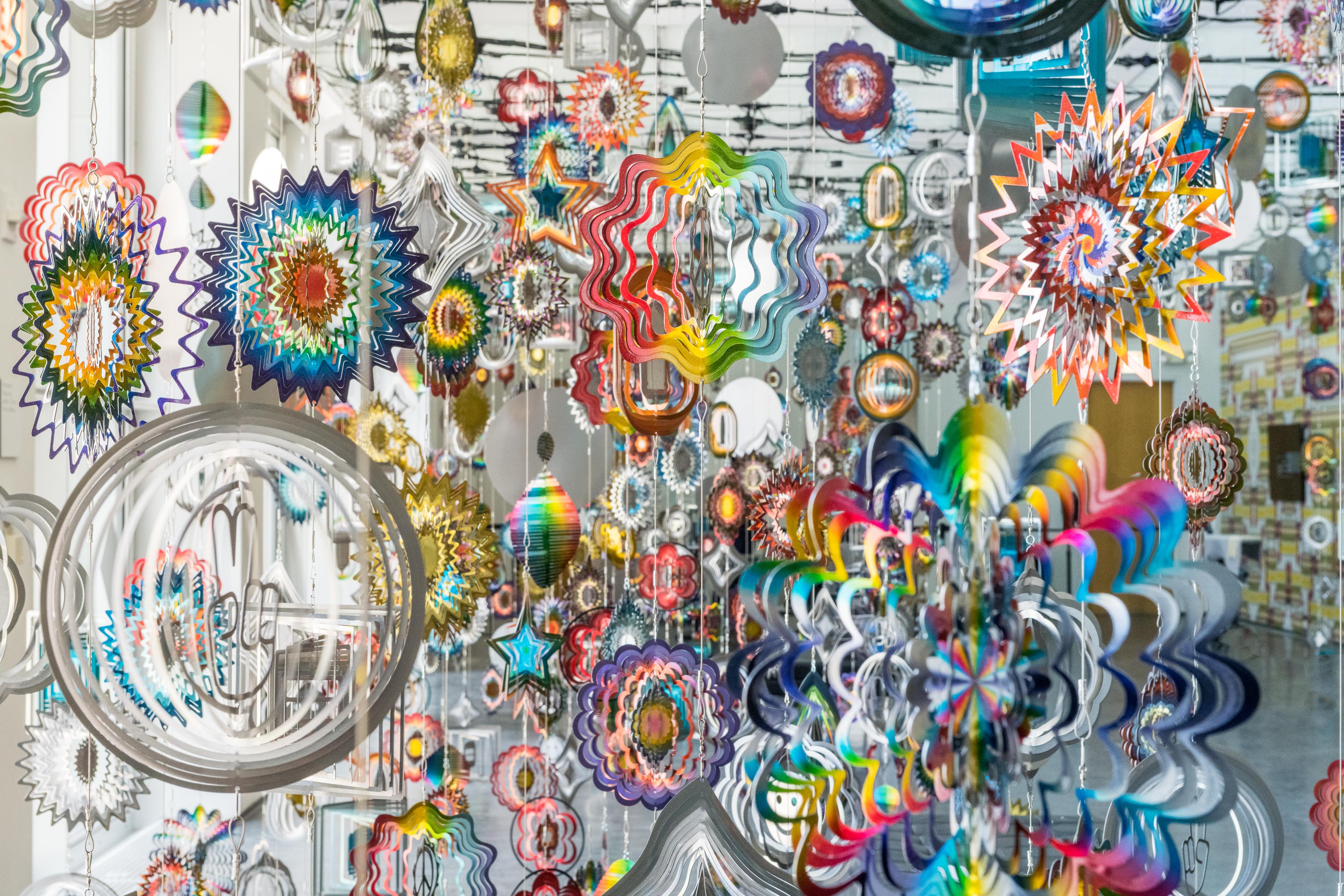 kinetic ornaments hang to form a tapestry of colorful shapes and patterns