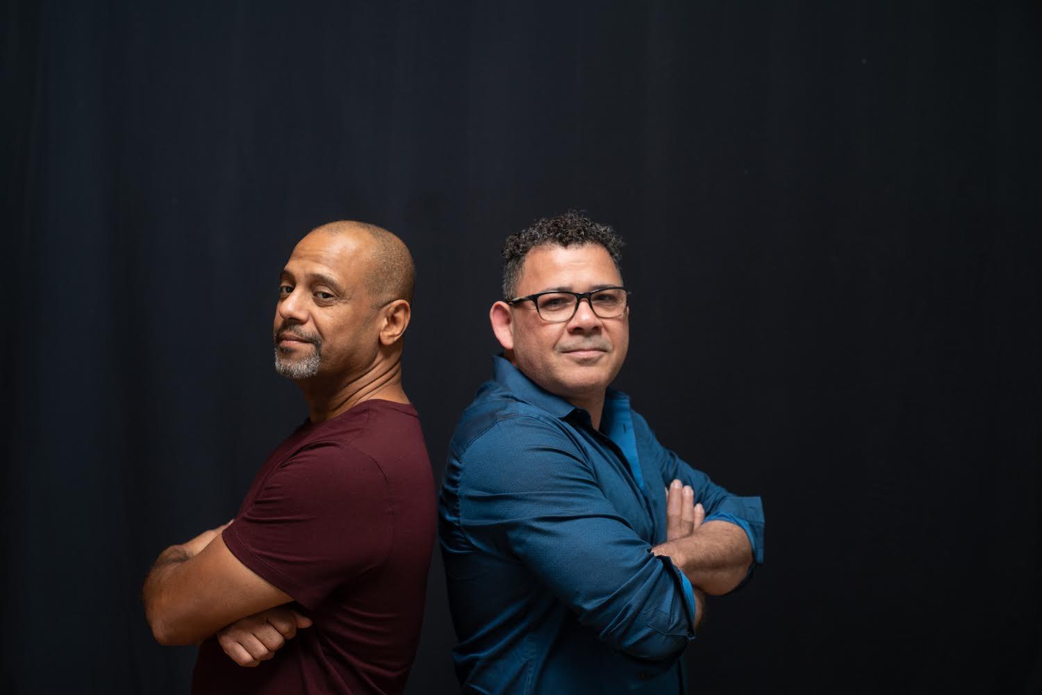 Two men with arms crossed standing back to back