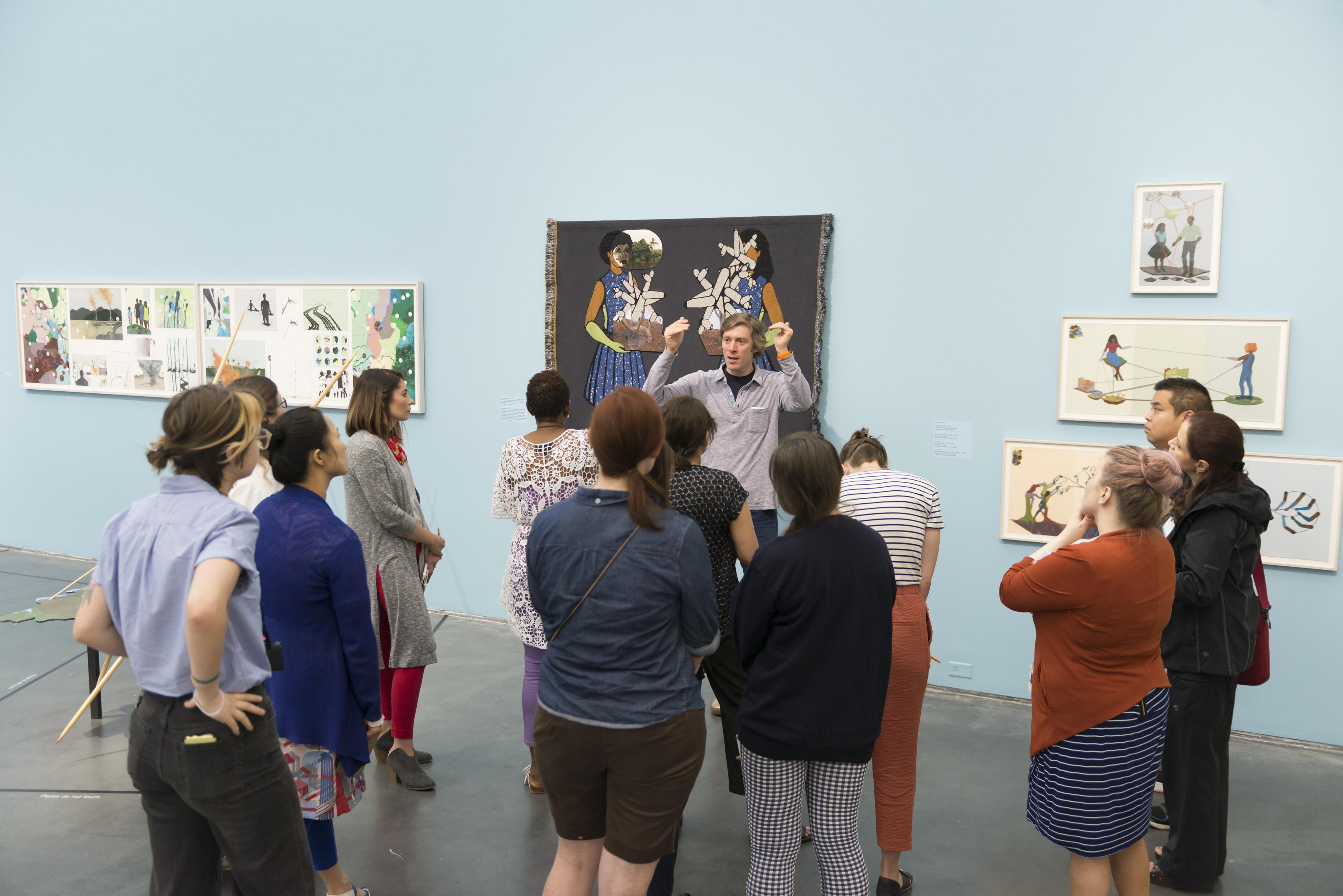 A group stands around a speaker in a gallery