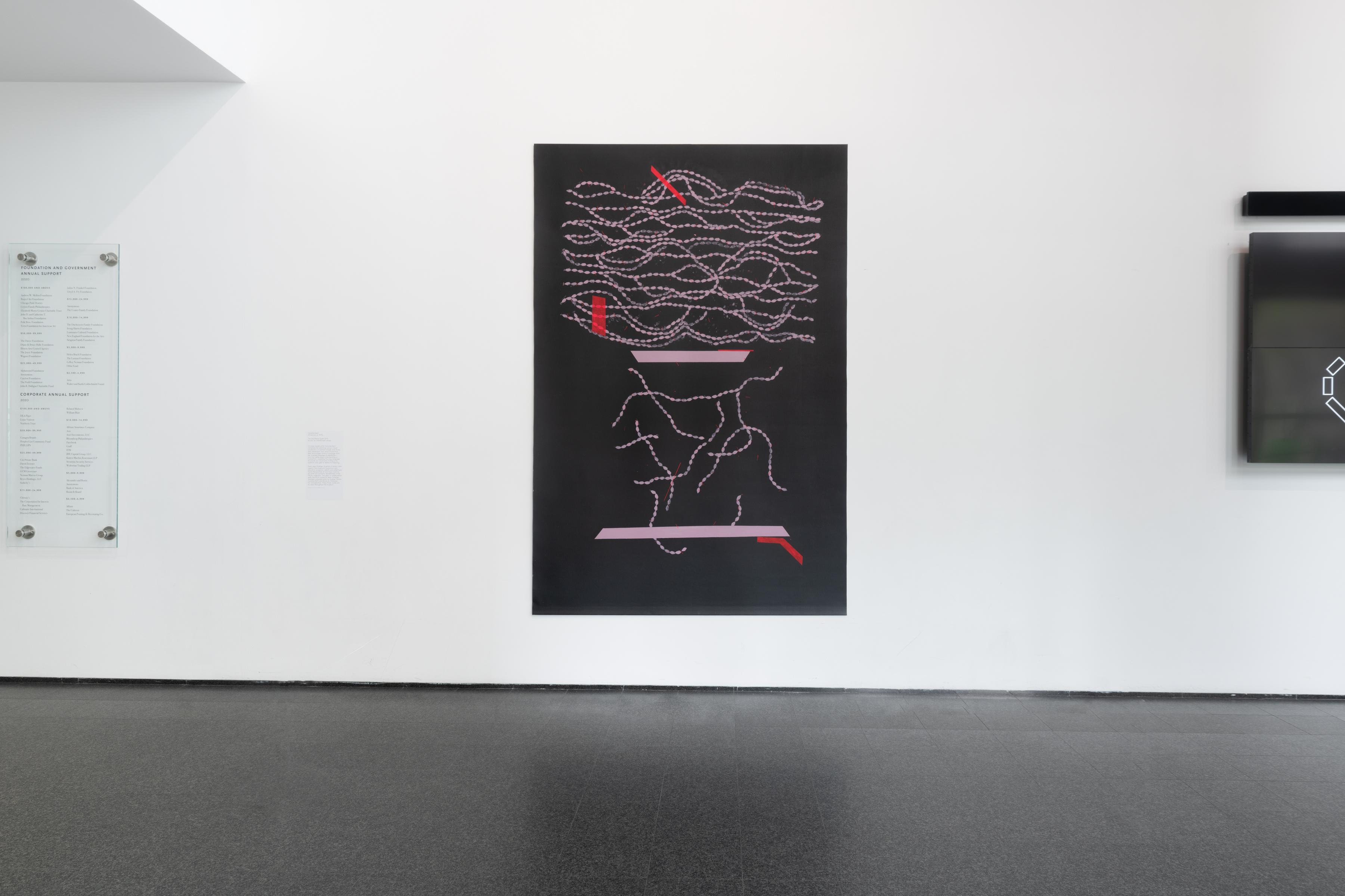 An artwork featuring white, seemingly abstract lines and accents of thick red and pink lines against a black background hangs on a white wall between a clear placard and an unidentifiable object.