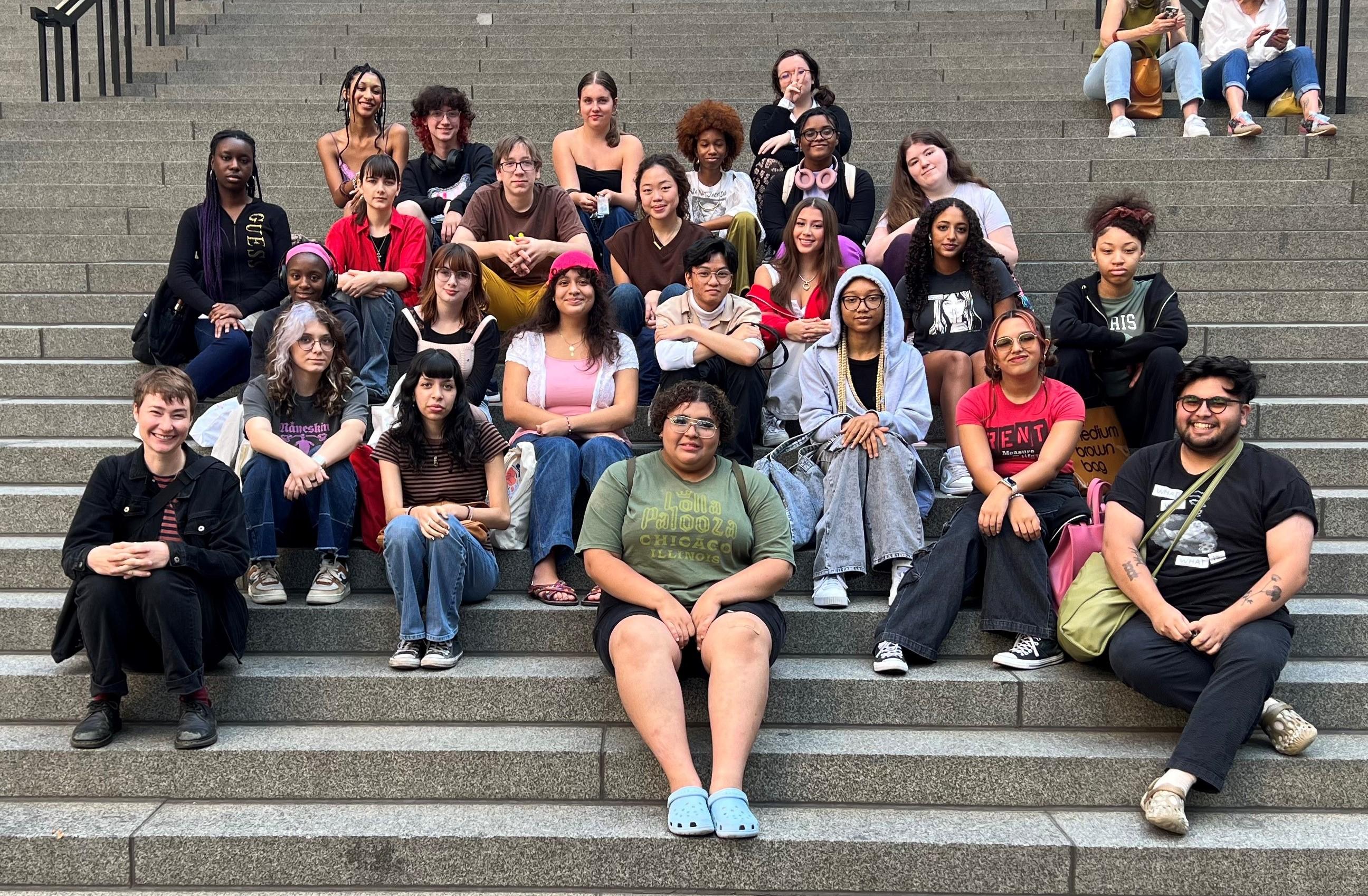 Group portrait of people of various ethnicities sitting on wide gray steps.