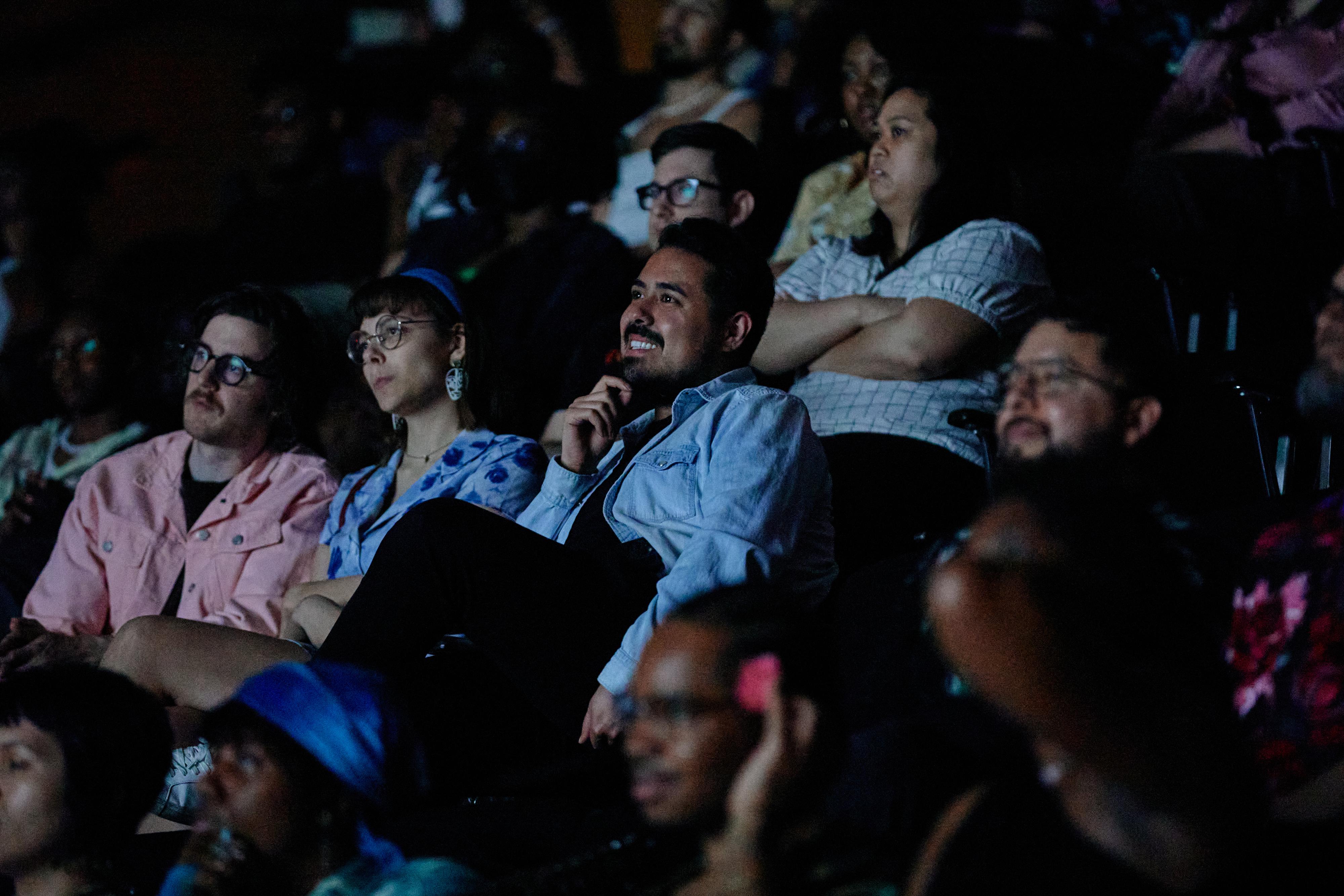 Candid photo of an audience in a darkened theater.