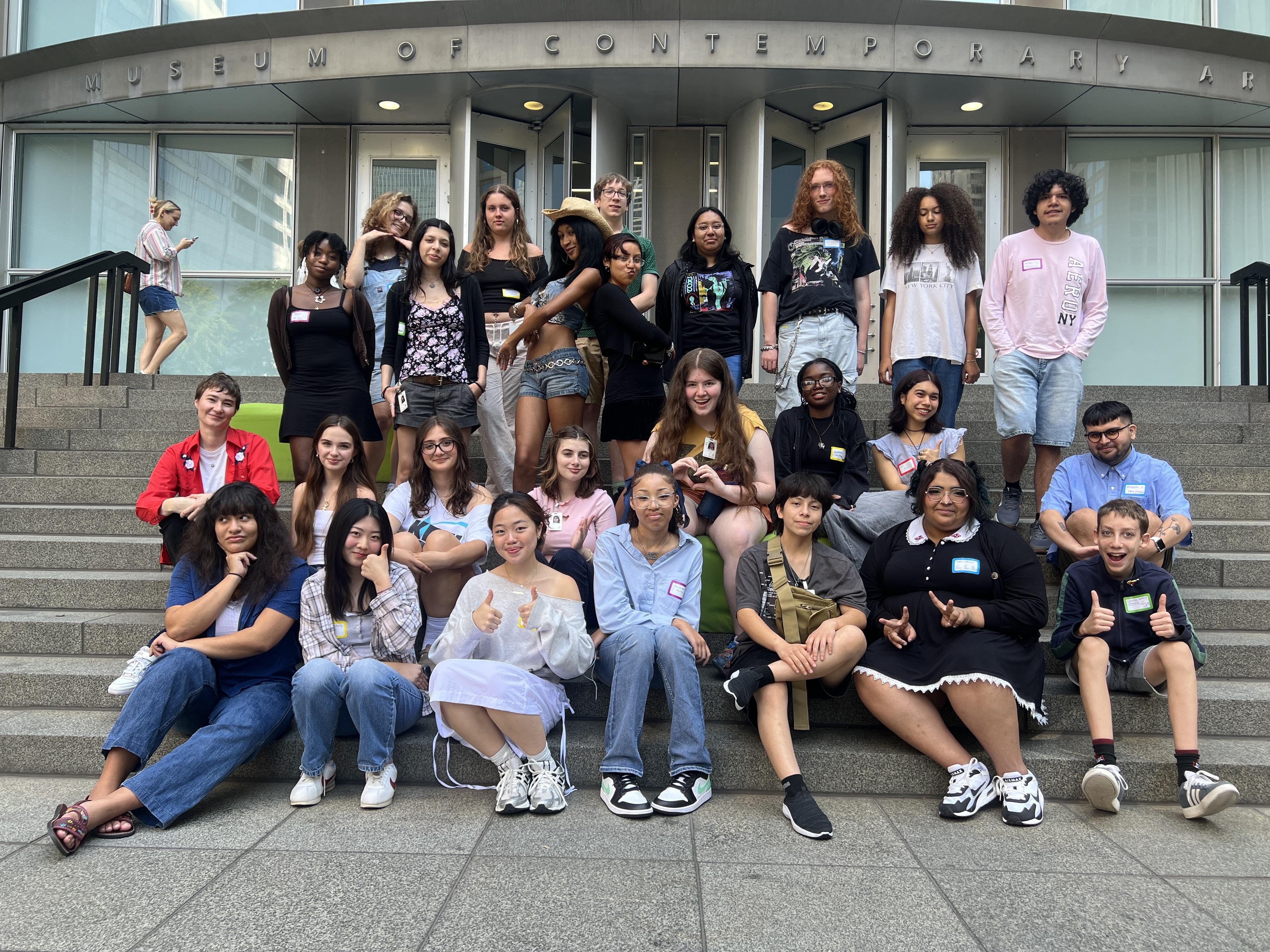 Group portrait of youth of various ethnicities on grey steps in front of the Museum of Contemporary Art's second floor entrance