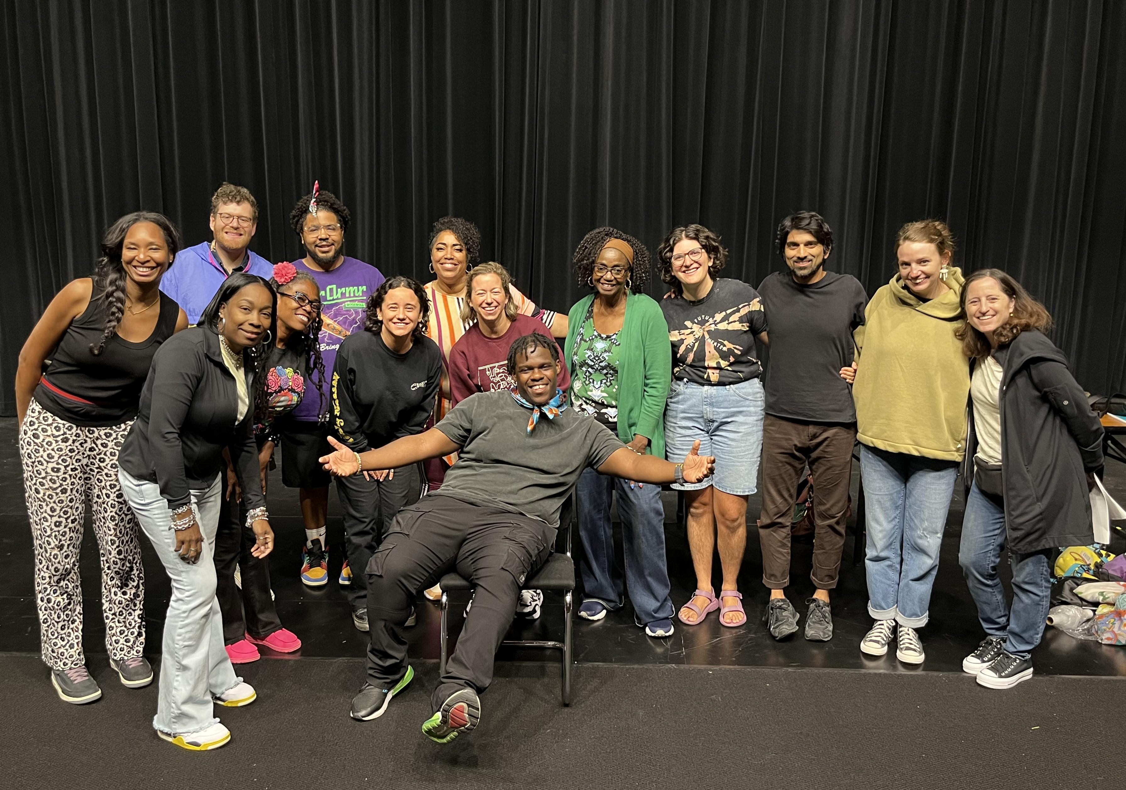 Group portrait of people of various ethnicities in front of a black curtain