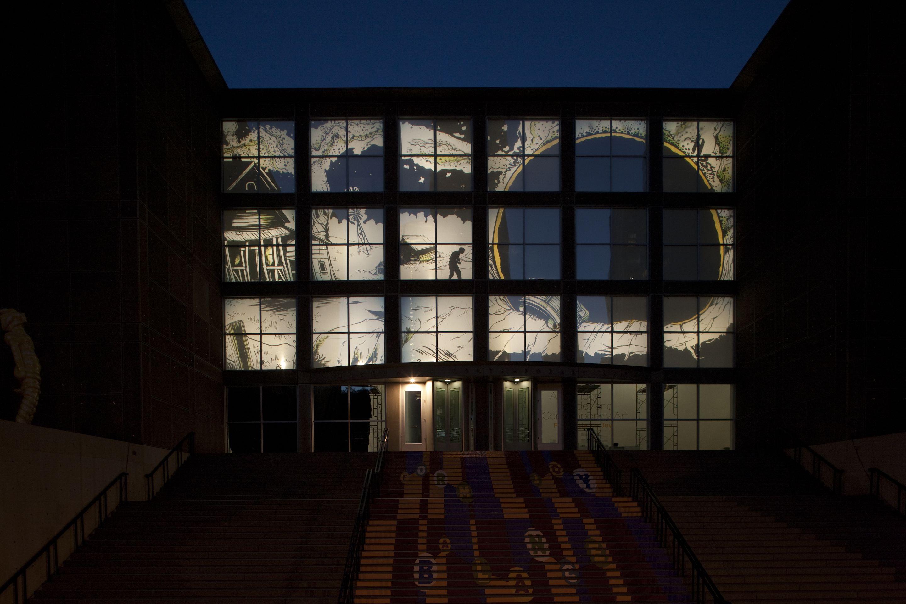 A projection on three floors of a building featuring a large dark orb near a house